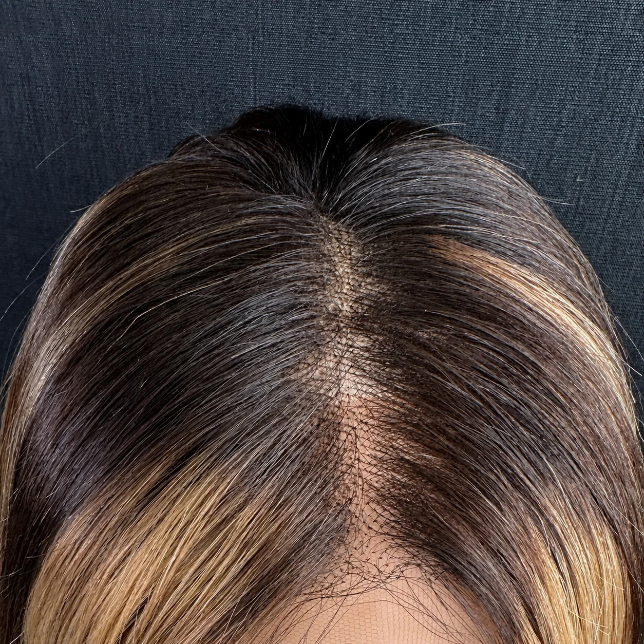 Hand-painted balayage wig close-up of dark roots, the parting and lace hairline